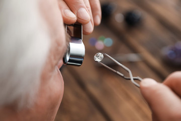 Male jeweler evaluating precious gemstone in workshop, closeup