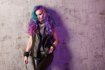 Daring rebel rocker, in black leather clothes with colored hair. Young stylish woman with trendy gradient toning hair