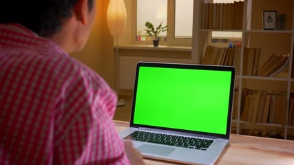 Closeup back view shoot of indian young businessman having a video call on the laptop with green screen in the office indoors