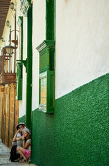 mother and daughter sitting by the door of an old colonial house