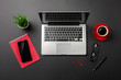 Black office desk table with blank screen laptop computer, notebook, mobile phone and red cup of coffee