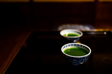 Traditional japanese cups with matcha or mulberry green tea in ryokan with black lacquered wood table