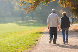 Senior citizen couple taking a walk in a park during autumn morning.