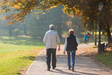 Senior citizen couple taking a walk in a park during autumn morning.