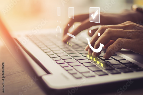 Cuadros en Lienzo Businesswoman pressing face emoticon on the keyboard laptop / Customer service evaluation concept