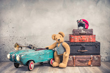 Teddy Bear Toy Standing Near Rusty Retro  Pedal Car From 60s, Antique Travel Trunks Luggage, Old Leather Valises, Red Helmet With Outdated Goggles Front Loft Background. Vintage Style Filtered Photo