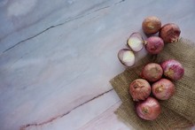 Fresh Red Onion On A Sack Cloth Againts A Marble Background