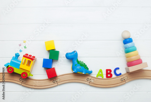 Naklejki do przedszkola kids-toys-on-toy-wooden-railway-on-white-wooden-background-with-copy-space