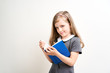 © briagin - Little girl photographed against white background wearing school uniform dress isolated holding open blue book
