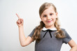 © briagin - Little girl photographed against white background wearing school uniform dress isolated pointing with index finger
