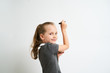 Little girl photographed against white background wearing school uniform dress isolated is mocking writing with marker