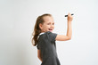 © briagin - Little girl photographed against white background wearing school uniform dress isolated is mocking writing with marker