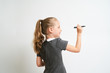 © briagin - Little girl photographed against white background wearing school uniform dress isolated is mocking writing with marker