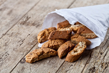 Wall Mural - Traditional Italian cookies cantuccini on white paper bag on ructic wooden table background.