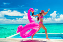 Vacation Fun Woman In Bikini With Funny Inflatable Pink Flamingo Pool Float Running Of Joy Jumping By Infinity Swimming Pool. Girl Enjoying Travel Holidays At Resort Luxury Overwater Bungalow Travel.