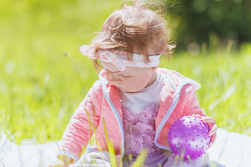 Playing little child with colored toys, outdoors, summer time