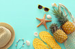 Ripe pineapple and beach sea life style objects over pastel mint blue wooden background. Tropical summer vacation concept