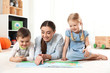© New Africa - Kindergarten teacher reading book to children indoors. Learning and playing