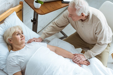 overhead view of sick senior woman with husband in clinic