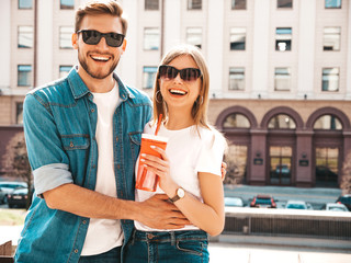 Portrait of smiling beautiful girl and her handsome boyfriend in casual summer clothes. Happy cheerful family having fun on the street background in sunglasses. Woman with bottle of water and straw