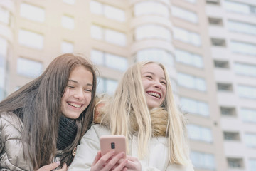 young teenage hipster girls laugh staring at smartphone