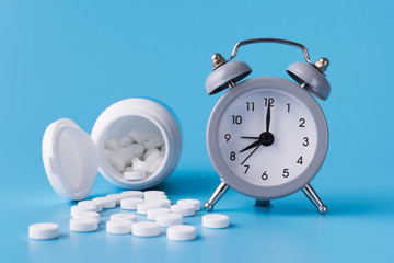 Wall Mural - clock with alarm clock stand on a blue background and show the exact time for the taking of medications next to them medical talbetas for treatment of diseases