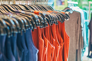 Wall Mural - Interior of fashion clothes store with different women clothes on hangers in red, blue and other colors.