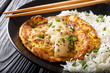 Egg foo yong fried egg patty containing vegetables  and meat with rice garnish close-up on a plate. Horizontal
