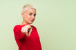 © luismolinero - Teenager girl with white short hair over green wall points finger at you with a confident expression