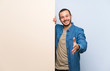 © luismolinero - Colombian man holding an empty placard handshaking after good deal