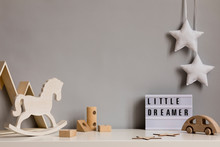 Stylish And Cozy Childroom With Wooden Mountain Box, Toys, Rocking Horse, Blocks And Hanging White Stars On The Gray Wall. Bright And Sunny Interior. Copy Space For Inscription Or Product. Template. 