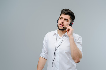 Wall Mural - Handsome middle eastern man working with headset answering business calls as tech support dispatcher isolated over grey background