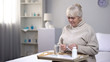 © motortion - Lonely senior woman taking pills in medical center, healthcare in old age