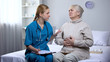 © motortion - Doctor supporting elderly patient, writing diagnosis in medical records, pain