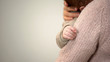 Young mother cuddling adorable infant in arms, tiny hand closeup, baby care