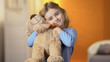 Beautiful girl with favourite teddy bear toy smiling at camera, happy childhood