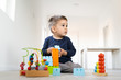 © Miljan Živković - Small boy playing with plastic brick block toys on the wooden floor at home
