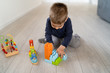 © Miljan Živković - Small boy playing with plastic brick block toys on the wooden floor at home
