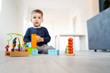 © Miljan Živković - Small boy playing with plastic brick block toys on the wooden floor at home