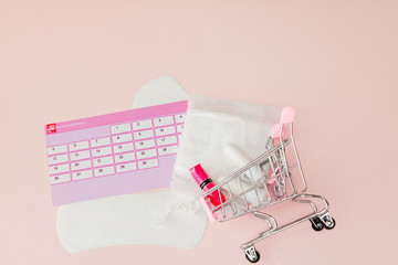 Tampon, feminine, sanitary pads for critical days, feminine calendar, pain pills during menstruation on a pink background. Tracking the menstrual cycle and ovulation