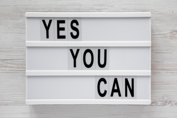 'Yes you can' words on a modern board over white wooden surface, top view. Overhead, from above. Flat lay. Close-up.