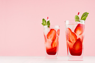 summer strawberry lemonade with green mint, ice cubes, striped straw on elegant pastel pink wall, wh