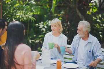 Wall Mural - Happy big family have a lunch at outdoor in green garden. Lunch or tea time on picnic table in summer. Big family outdoor lunch concept.