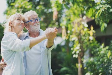 Wall Mural - Closed up senior Caucasian couple dancing felling happy in green garden. Grand father's birthday party in summer. Big family outdoor party concept.