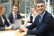 © ty - Businessman with colleagues in the background in office.