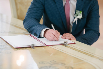 The room signs on the registration in the document on the wedding day