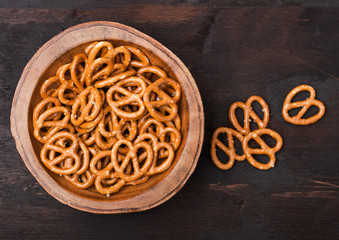 Hard salted pretzels classic snack for beer in wooden bowl on wooden background.