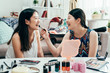 Friendship travel two asian young woman friends packing suitcase before going on holiday. happy smiling girls doing makeup helping each other in morning prepare for trip. laughing female roommates.