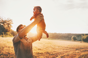 Father holding baby up in the air playing together family lifestyle daddy and child walking outdoor parenthood concept Fathers day holiday