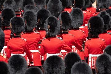 Close up of soldiers marching at the Trooping the Colour military parade at Horse Guards, London UK. Guards are wearing iconic black and red uniform and bearskin hats.